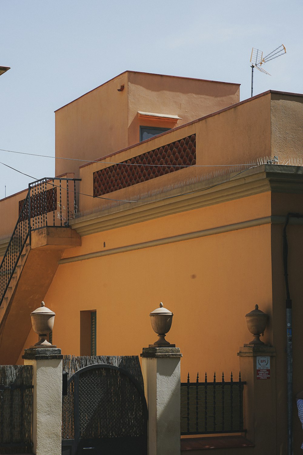 a yellow building with a black gate and a clock