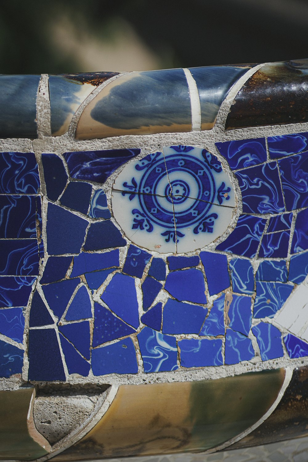 a close up of a blue and white mosaic tile bench