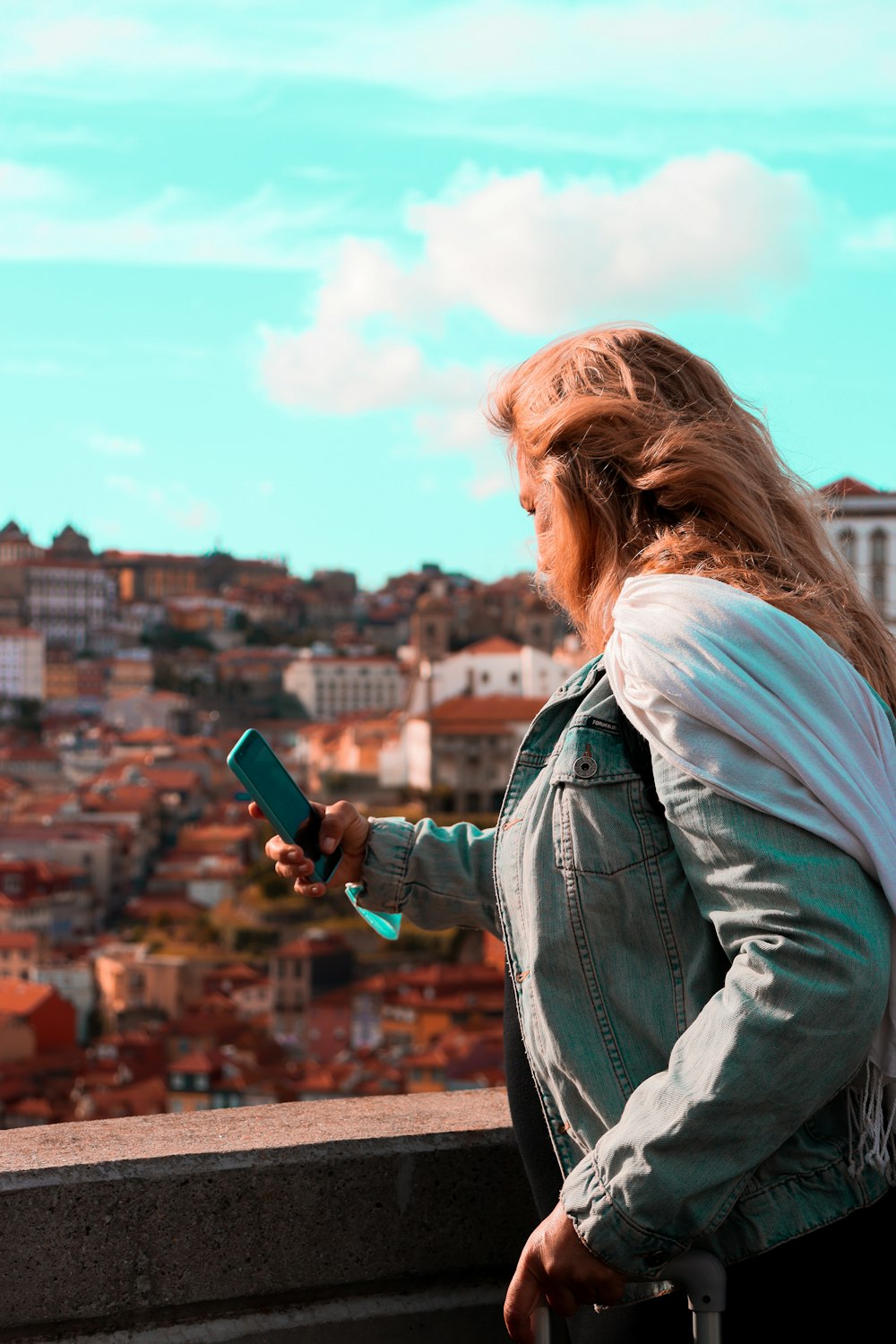 a woman looking at her cell phone while standing on a ledge