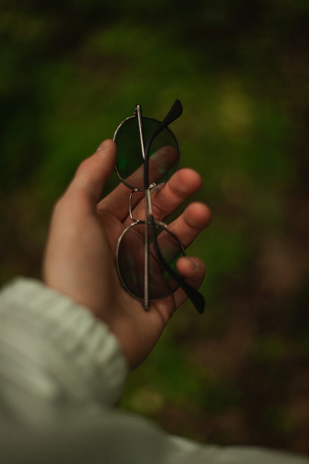 a person holding a pair of sunglasses in their hand