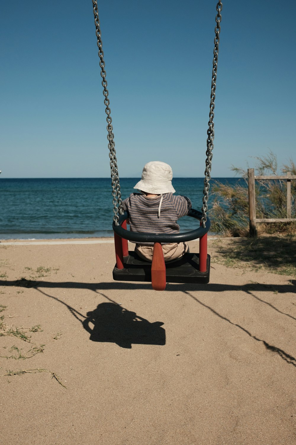 a person sitting on a swing at the beach