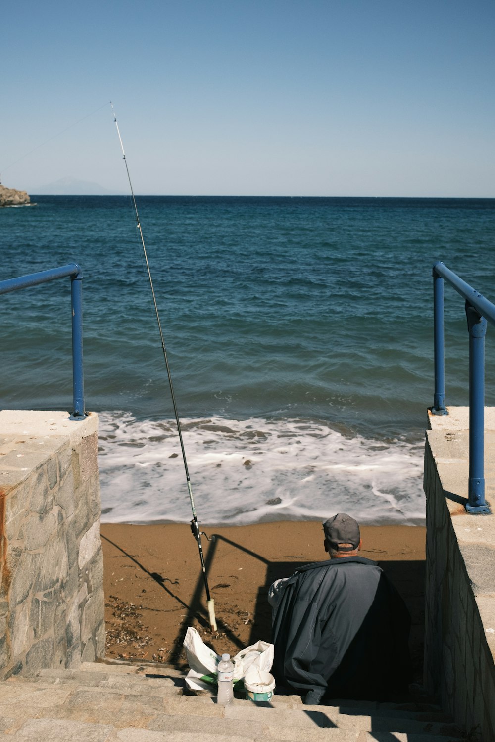 a man sitting on steps with a fishing rod