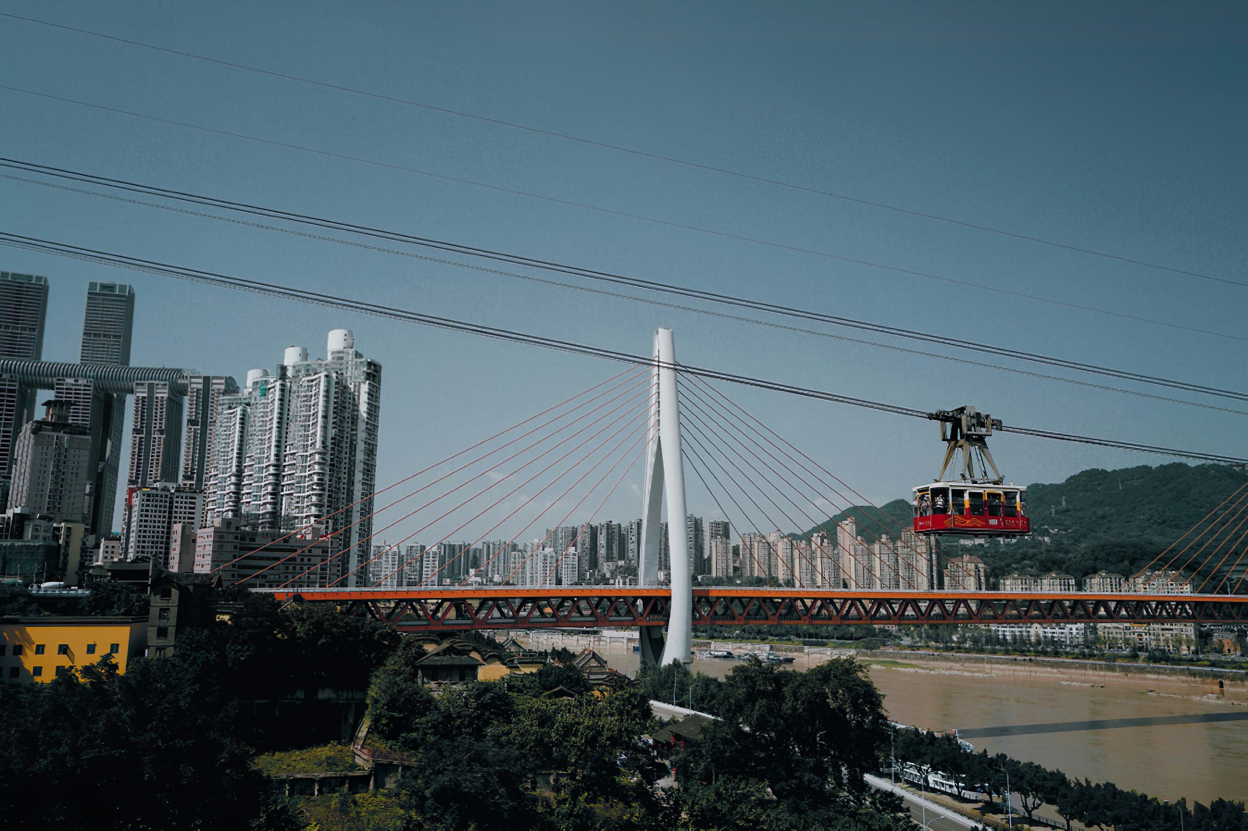a cable car going over a bridge with a city in the background