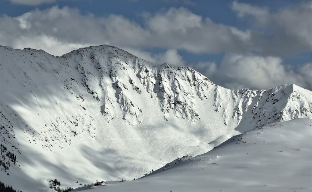 a mountain covered in snow under a cloudy sky