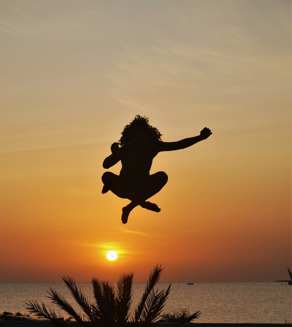 a silhouette of a person jumping into the air