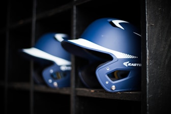 a row of baseball helmets sitting on top of a shelf