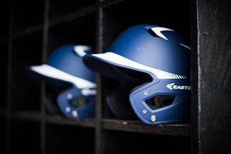 a row of baseball helmets sitting on top of a shelf