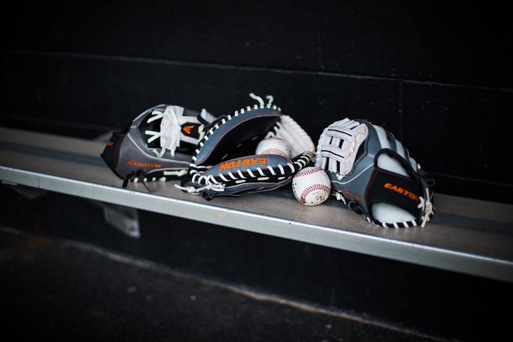 a pair of baseball gloves sitting on top of a metal shelf