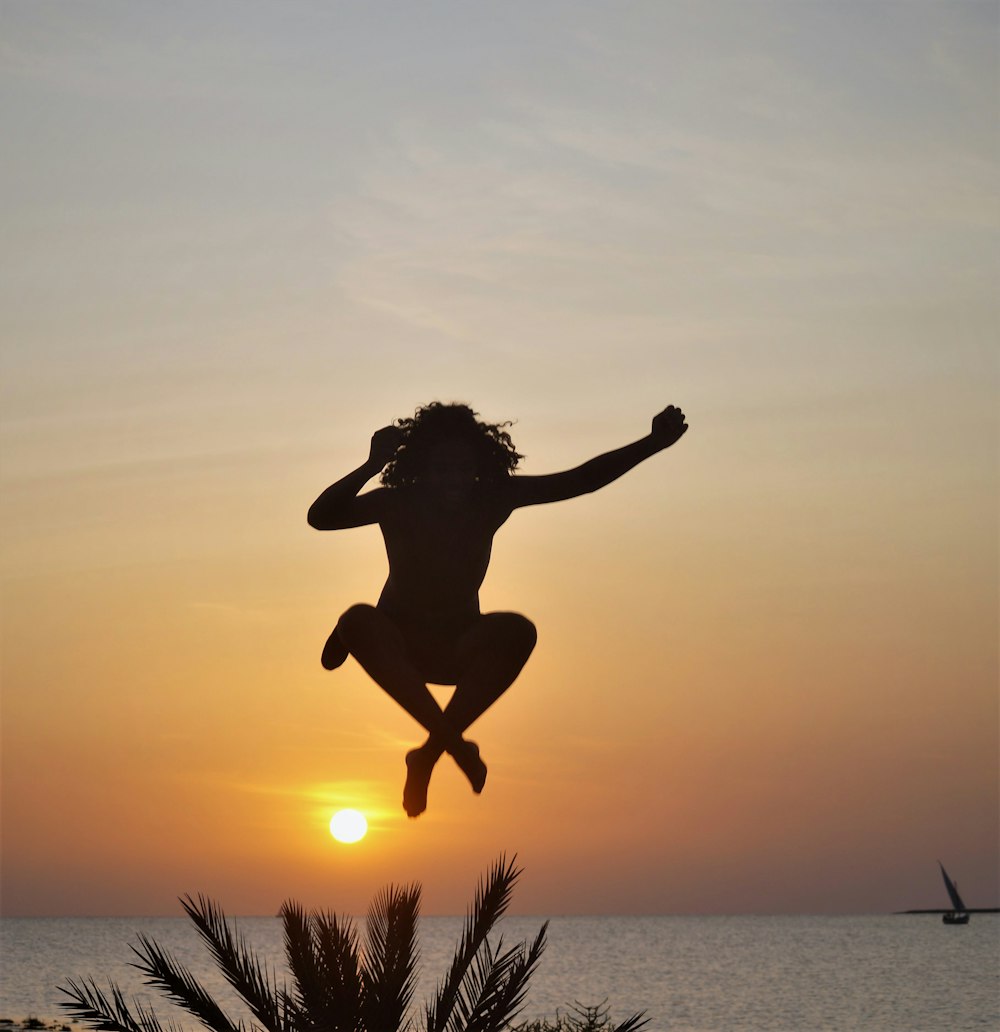 a silhouette of a person jumping into the air