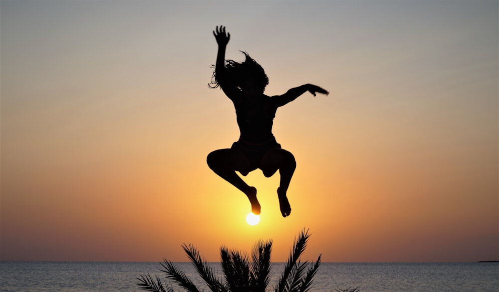 a silhouette of a person jumping into the air