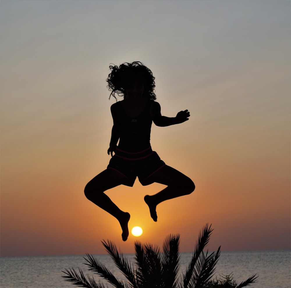 a silhouette of a woman jumping into the air