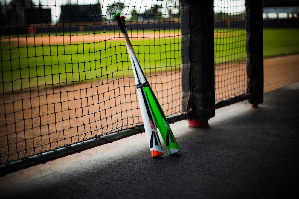 a baseball bat leaning against a fence on a baseball field