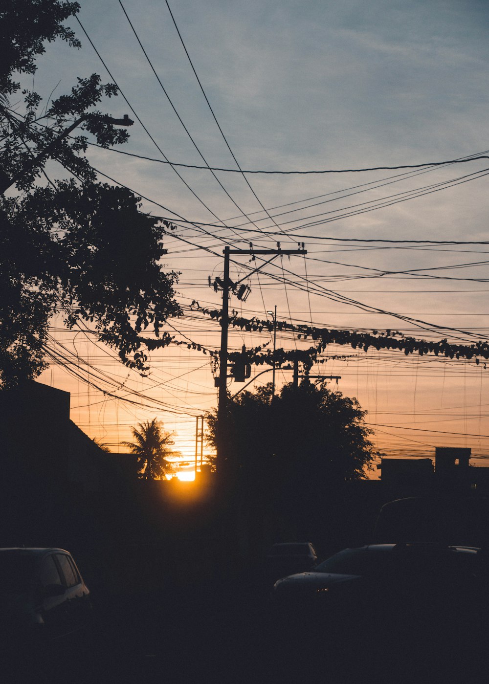 the sun is setting behind a telephone pole