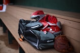 a baseball glove, catchers mitt, and helmet sit on a bench