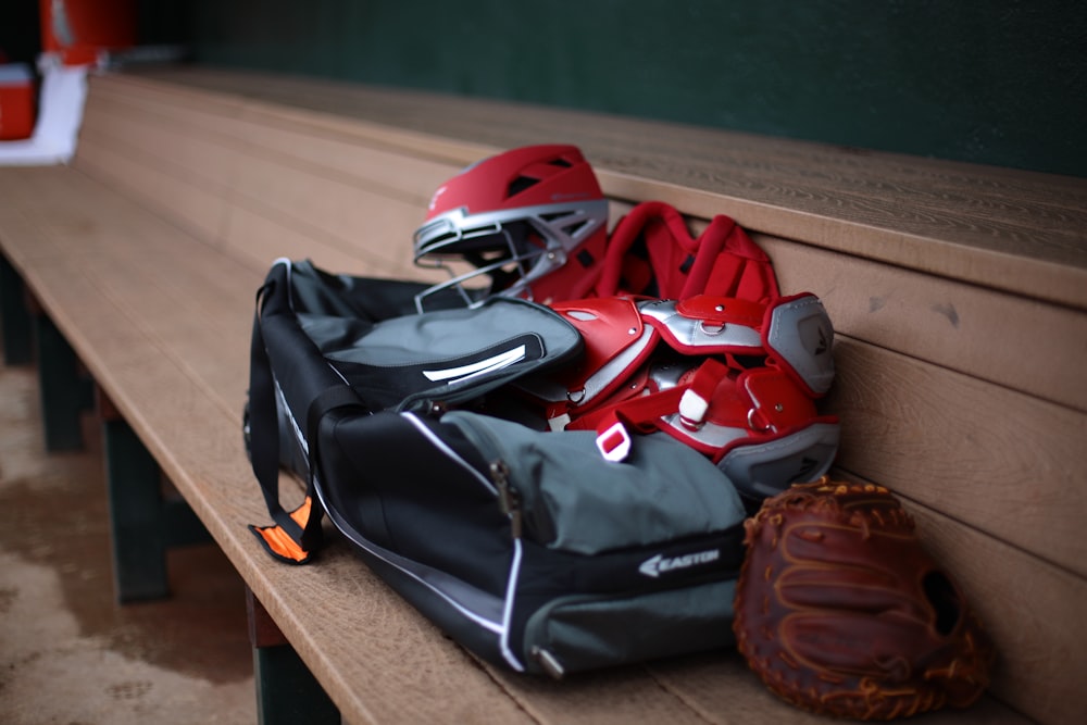 a baseball glove, catchers mitt, and helmet sit on a bench