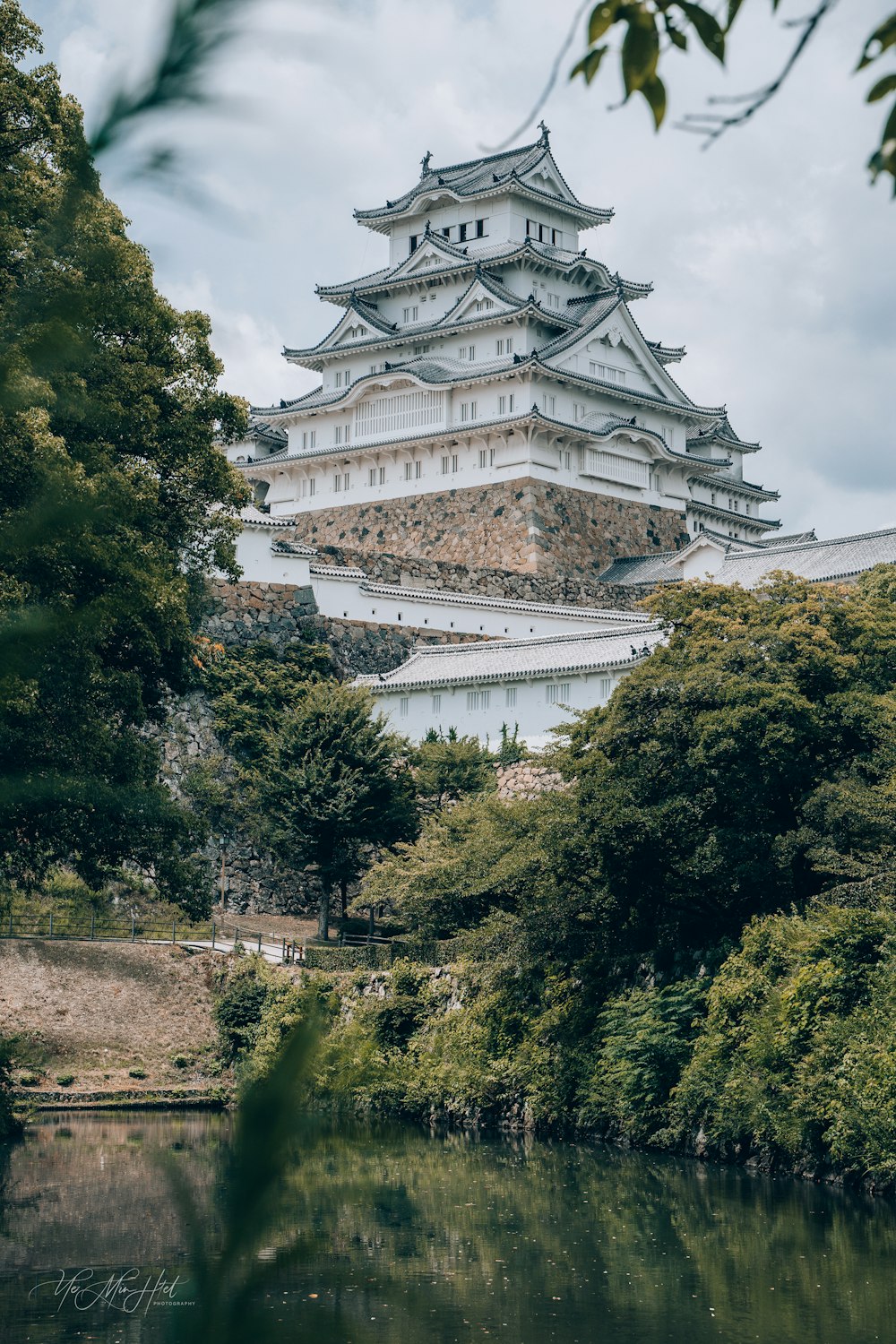 a tall white building sitting on top of a lush green forest