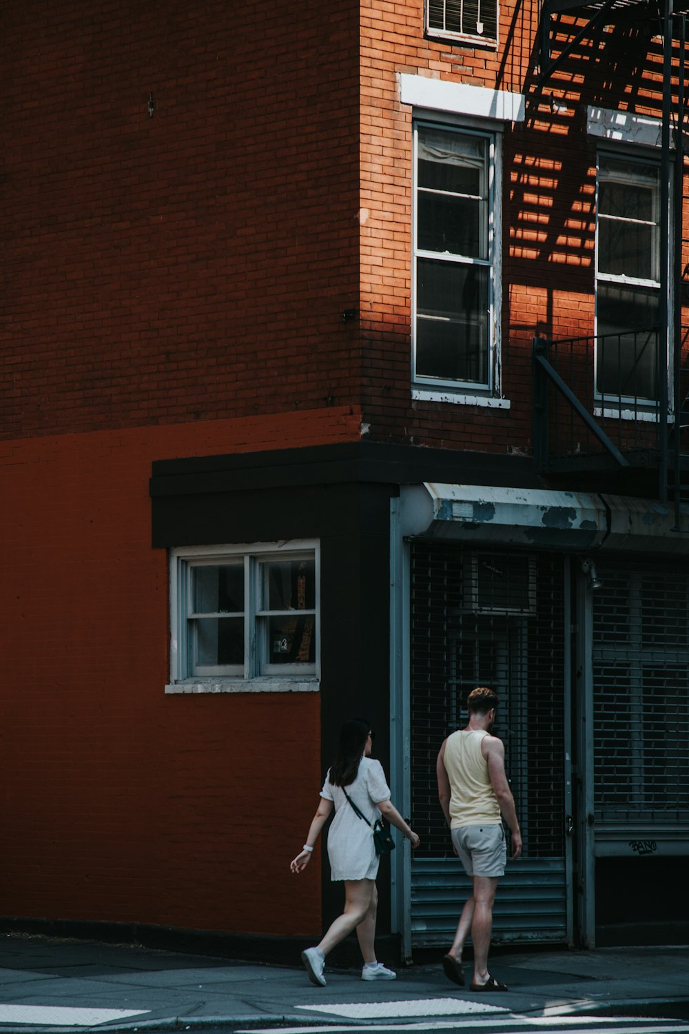 a man and a woman crossing the street in front of a building