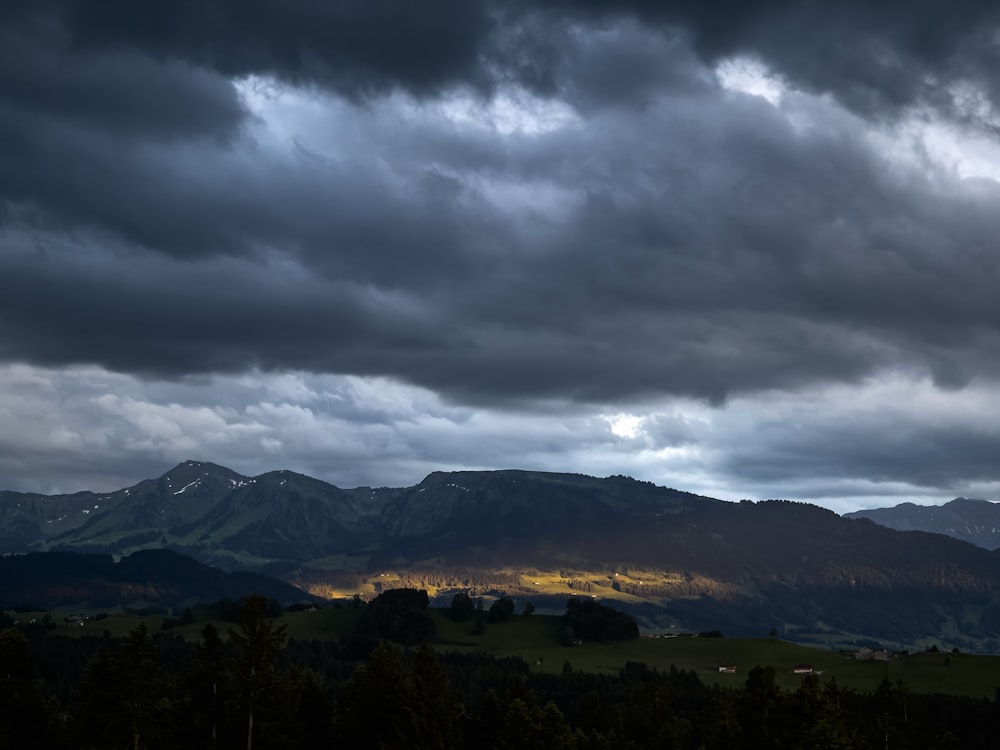 a dark cloudy sky with mountains in the background