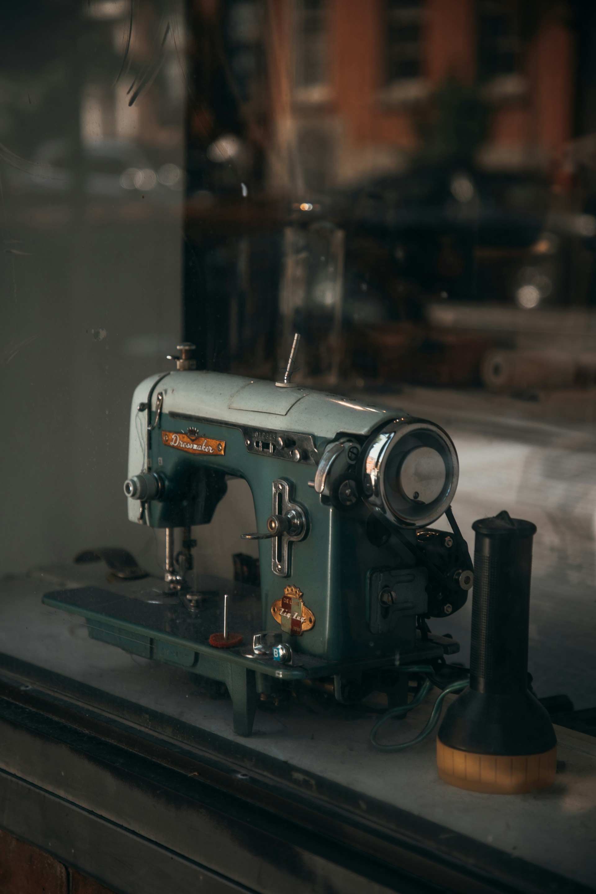 a green sewing machine sitting on top of a window sill