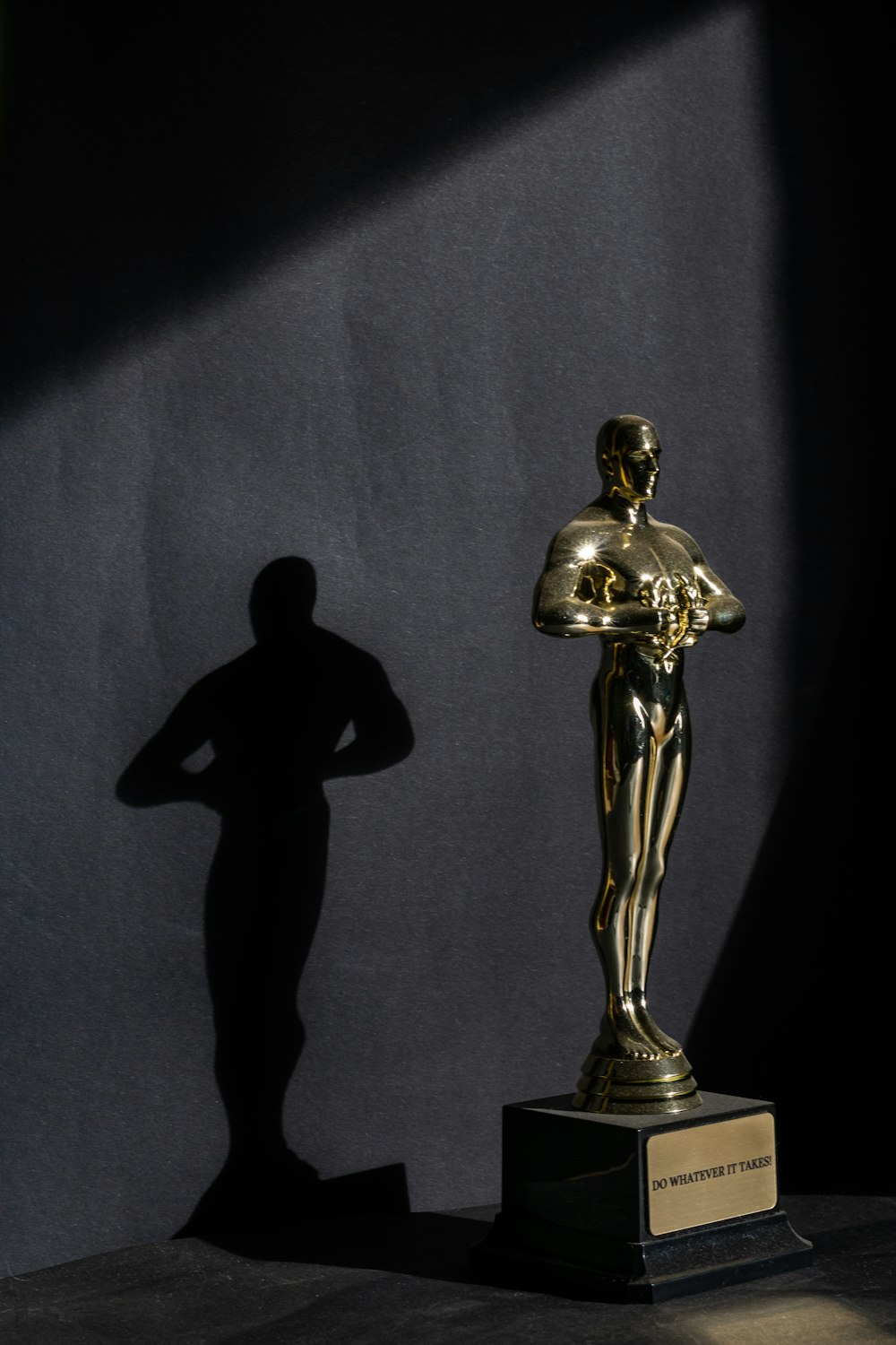 a golden statue of a man standing next to a black wall