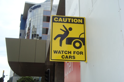 a yellow caution sign hanging on the side of a building