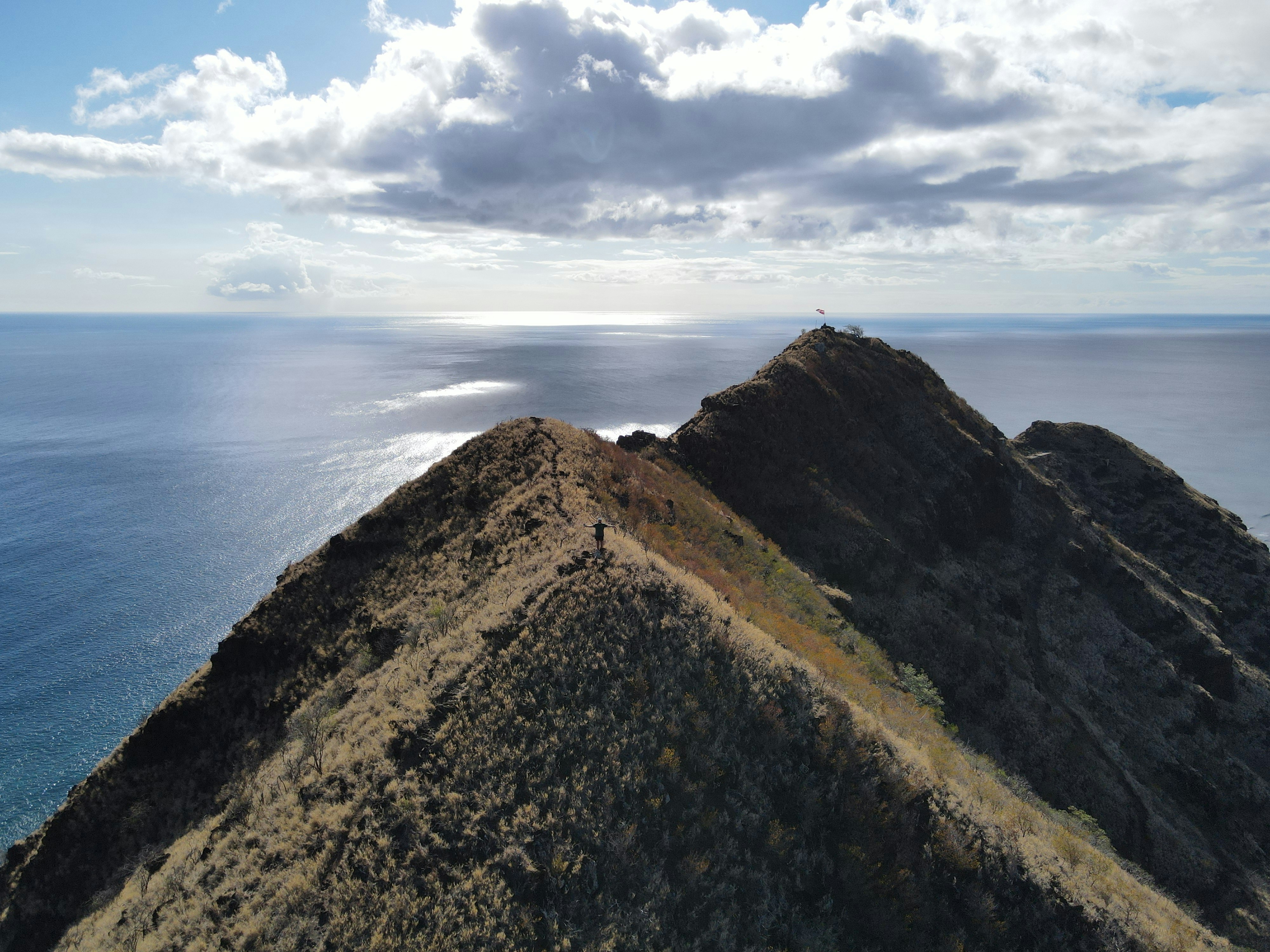 Trail runner on mountain ridge with ocean view