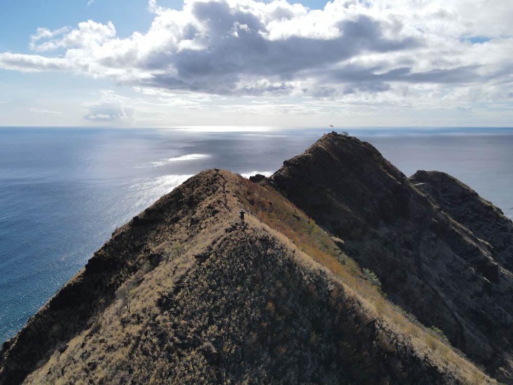 a person standing on top of a mountain next to the ocean