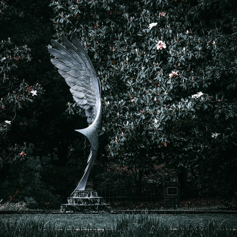 a large white bird flying over a lush green field