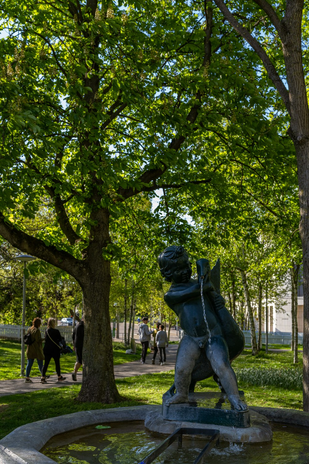 a statue of a boy is in the middle of a park