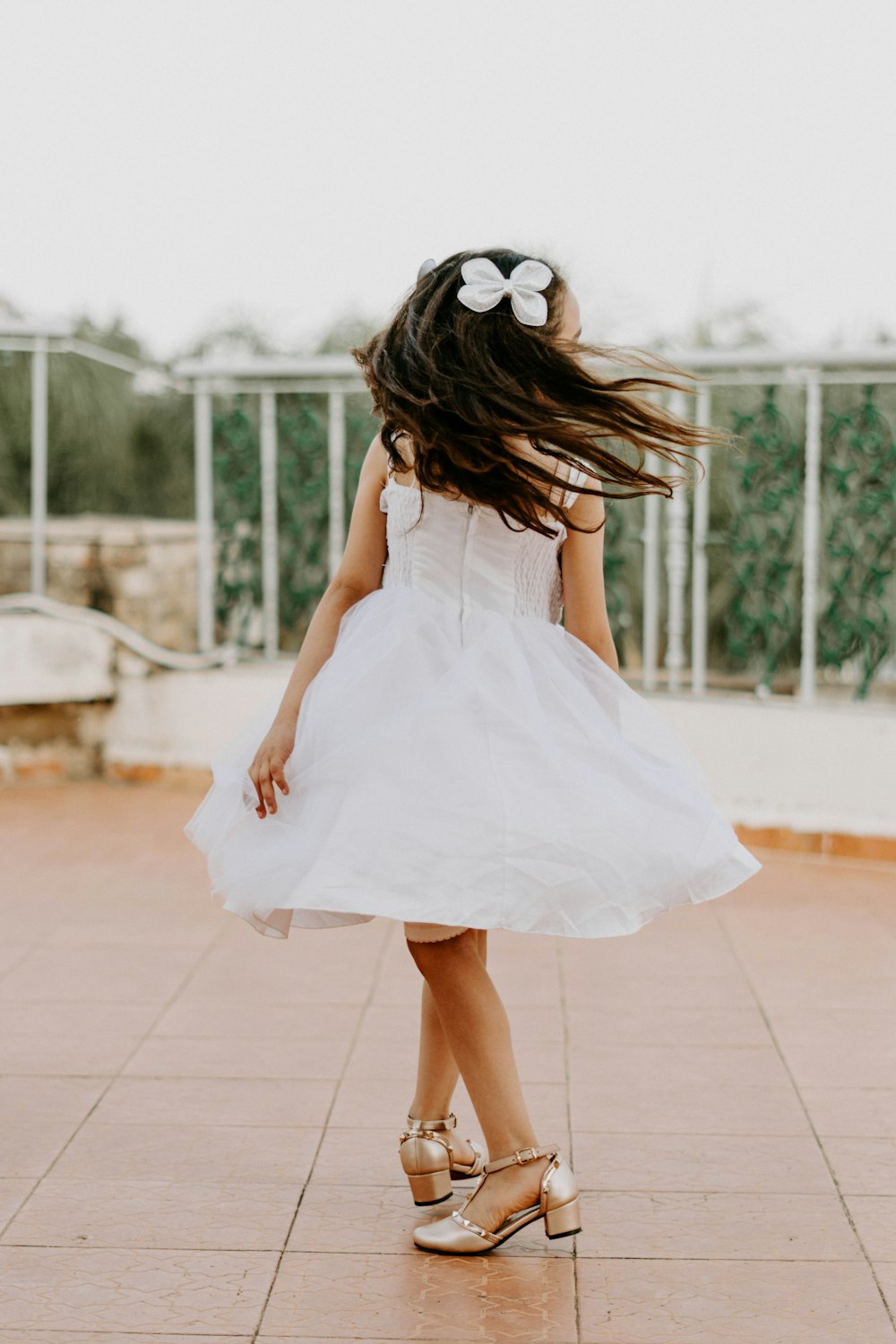 a little girl in a white dress with a flower in her hair