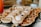 A close-up of a tray filled with an assortment of small pastries and savory tarts, some topped with whipped cream or garnished with herbs. Various textures and shapes are visible, including flaky crusts and creamy fillings, suggesting a variety of flavors.