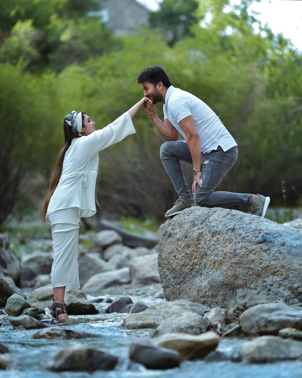 um homem e uma mulher de pé em uma rocha em um rio