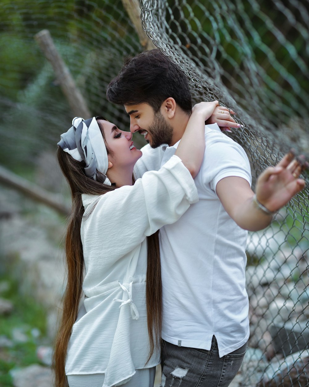 a man and a woman standing next to a fence