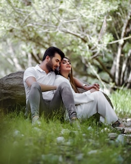 a man and a woman sitting next to each other in the grass