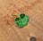A close-up of a vibrant four-leaf clover resting on a wooden table.