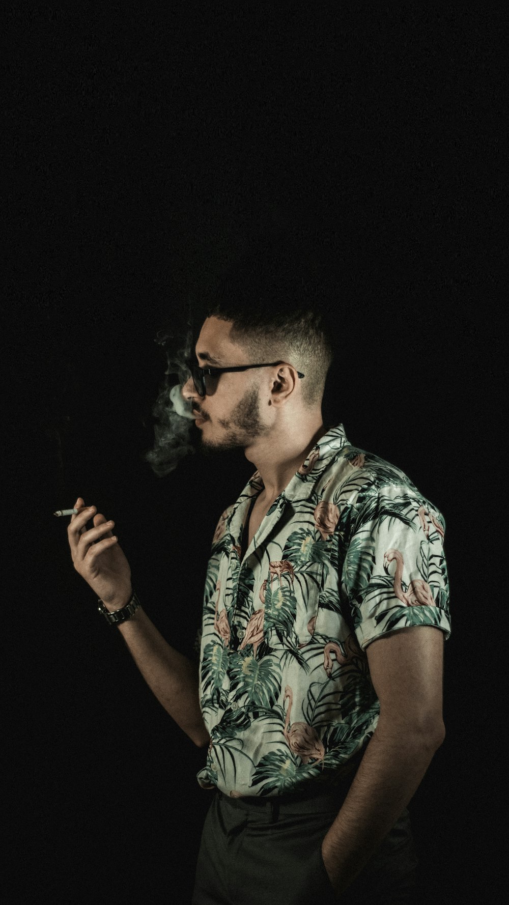 a man in a hawaiian shirt smoking a cigarette