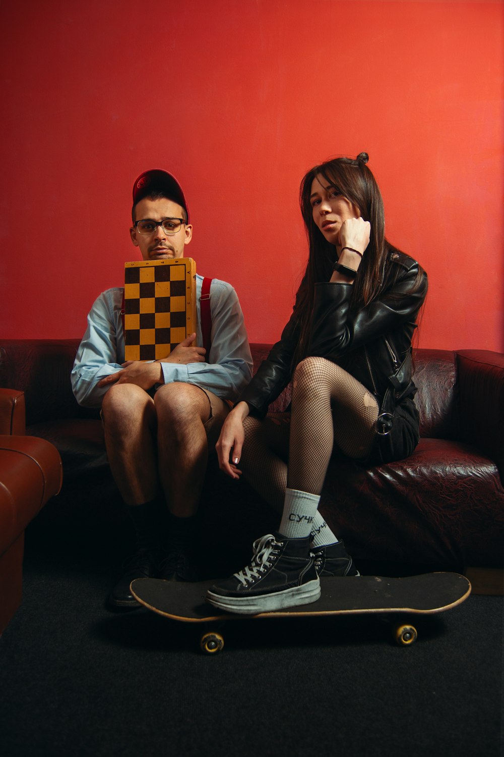 a man sitting on a couch next to a woman on a skateboard