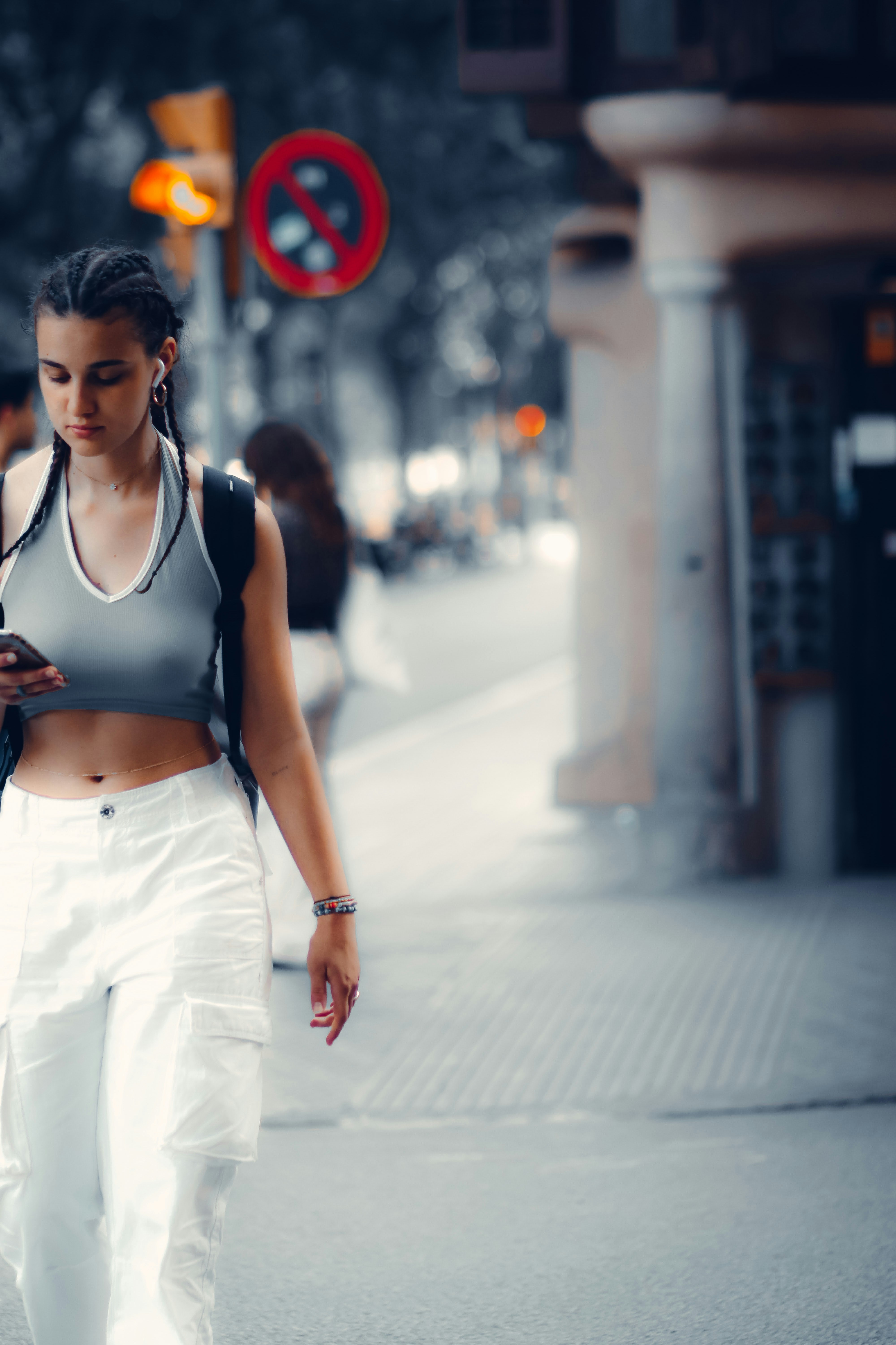 a woman walking down a street while looking at her cell phone