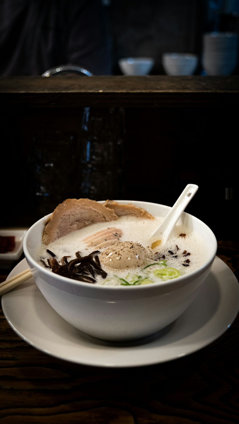 a bowl of soup on a plate with chopsticks