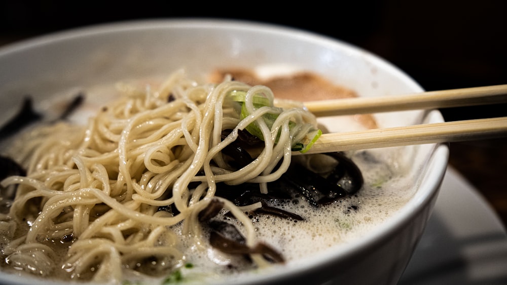 a bowl of noodles with chopsticks in it