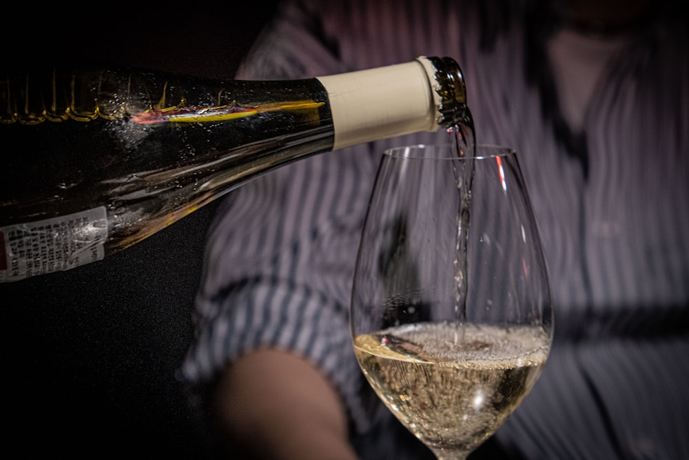 a person pouring a glass of wine into a wine glass