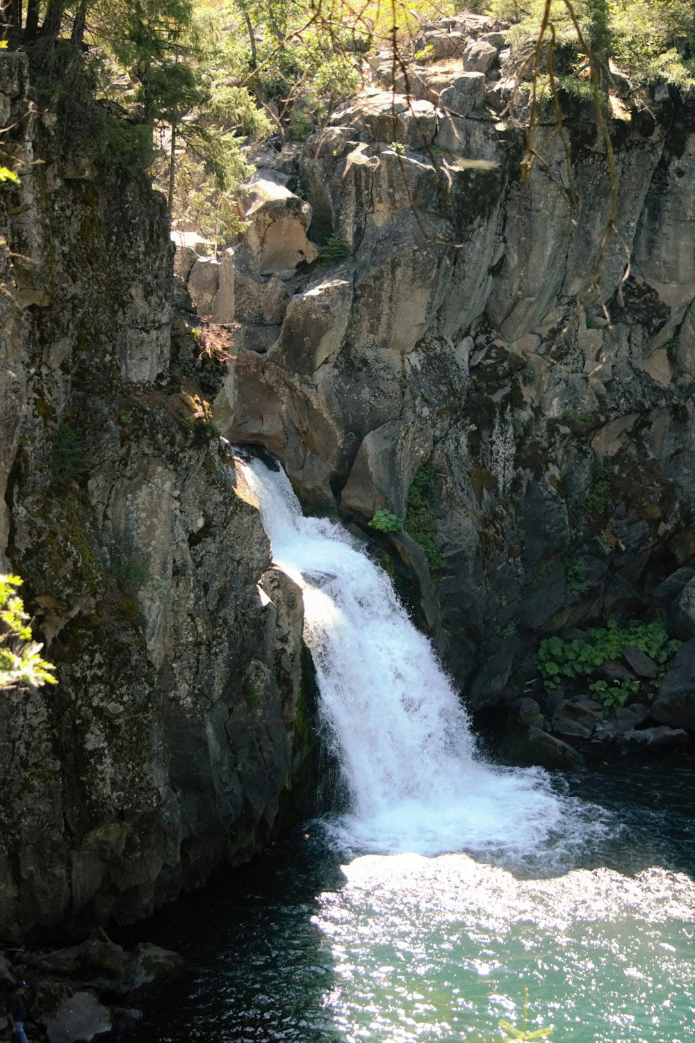 a small waterfall flowing into a river surrounded by rocks