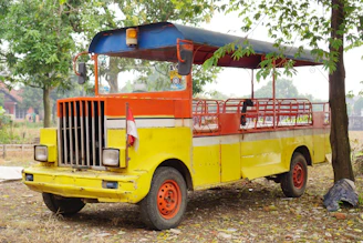 A Mitsubishi vehicle parked in front of a traditional Indonesian market with locals around.