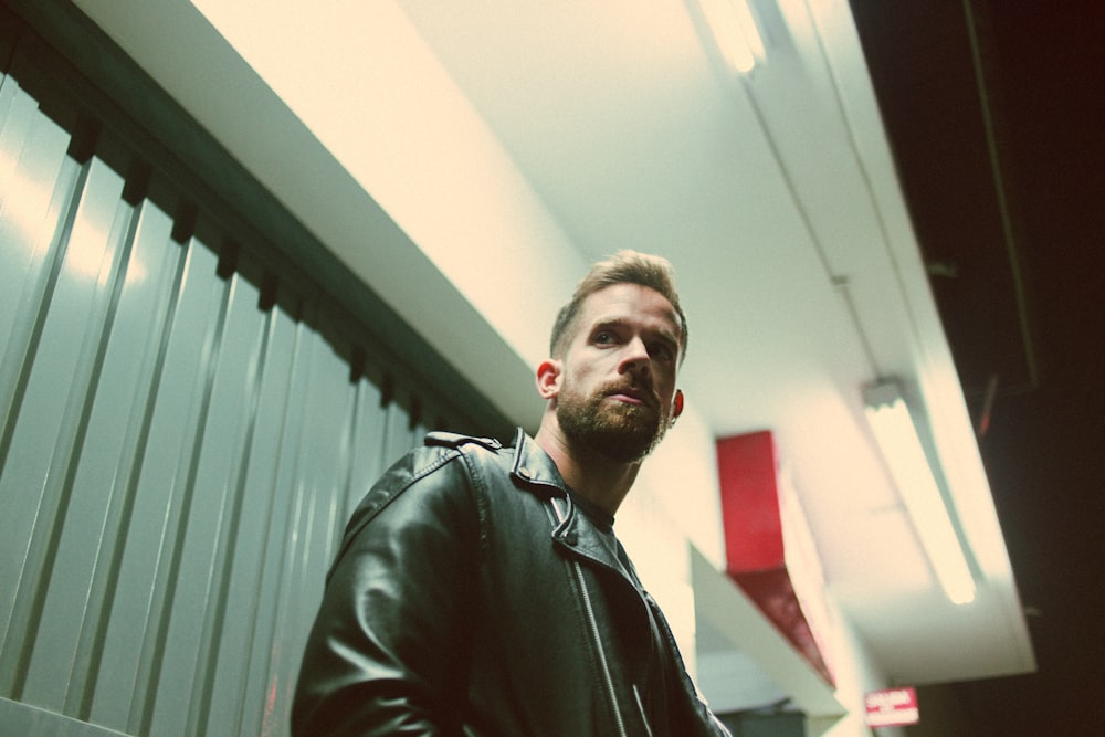 a man in a leather jacket standing in a hallway