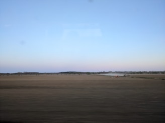 Construction workers preparing a green agricultural field with modern machinery under a clear blue sky.