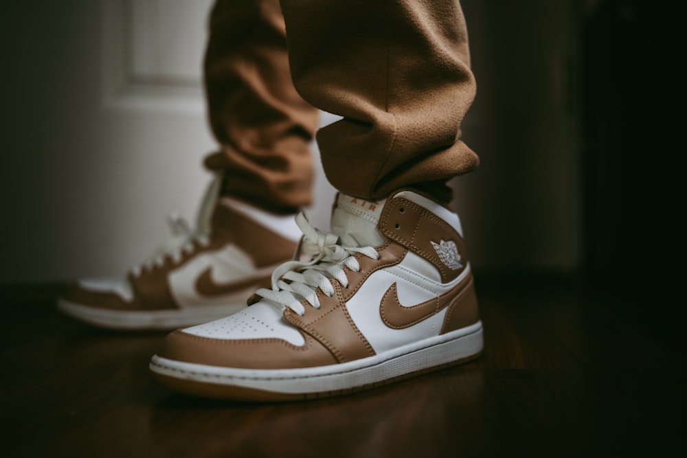 a pair of brown and white sneakers on a wooden floor