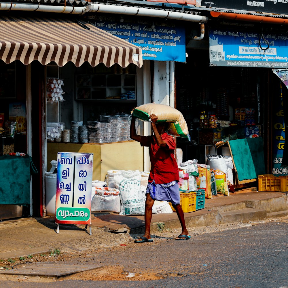 a man walking down a street carrying a large bag on his head