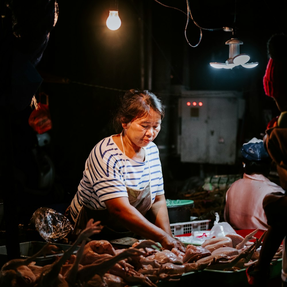 a woman standing in front of a table filled with meat