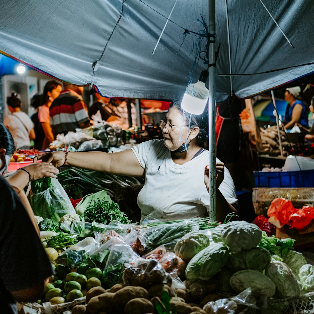 um homem em pé na frente de uma mesa cheia de frutas e legumes
