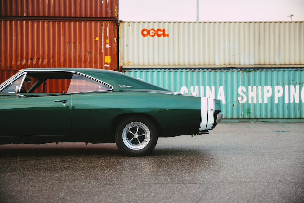 a green car parked in front of a shipping container